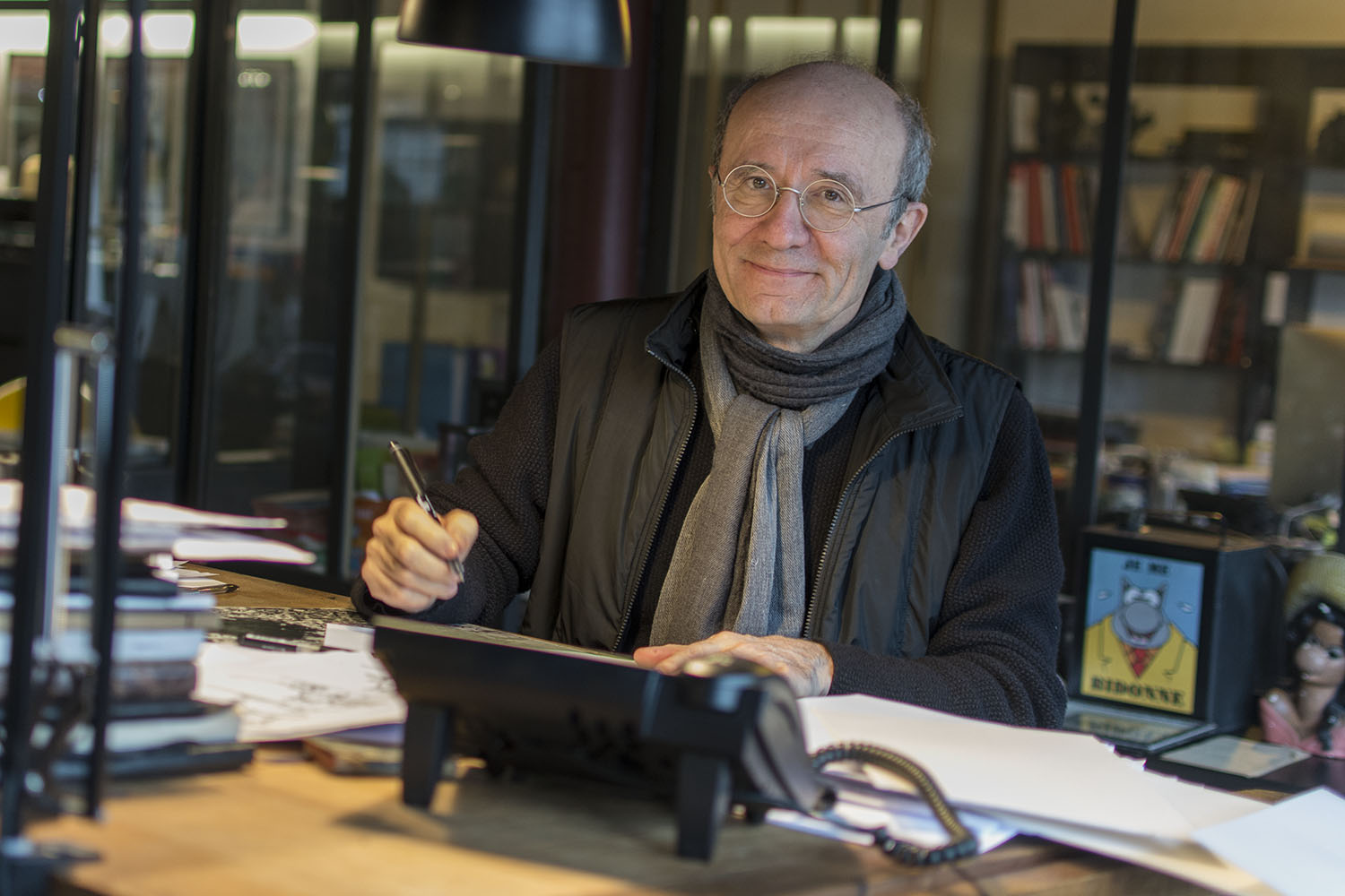 Philippe Geluck assis à sa table à dessin. C’est ici qu’il dessine quotidiennement le personnage du Chat pour la publication dans le journal Le Soir. 