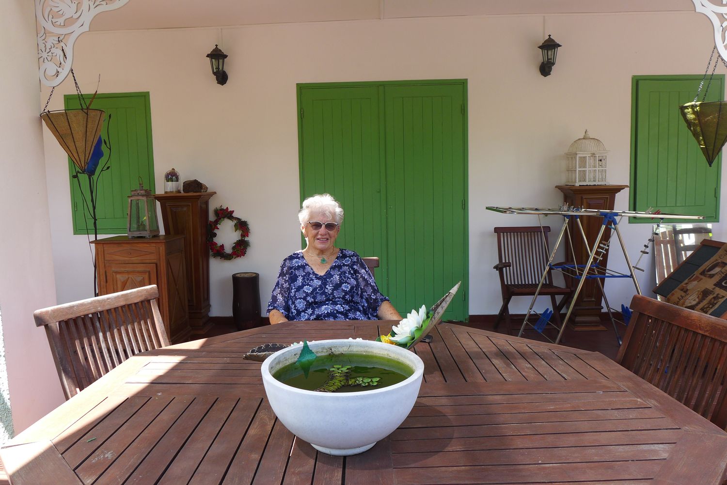 Ginette HOARAU assise à sa table de jardin, sous la varangue de sa maison.