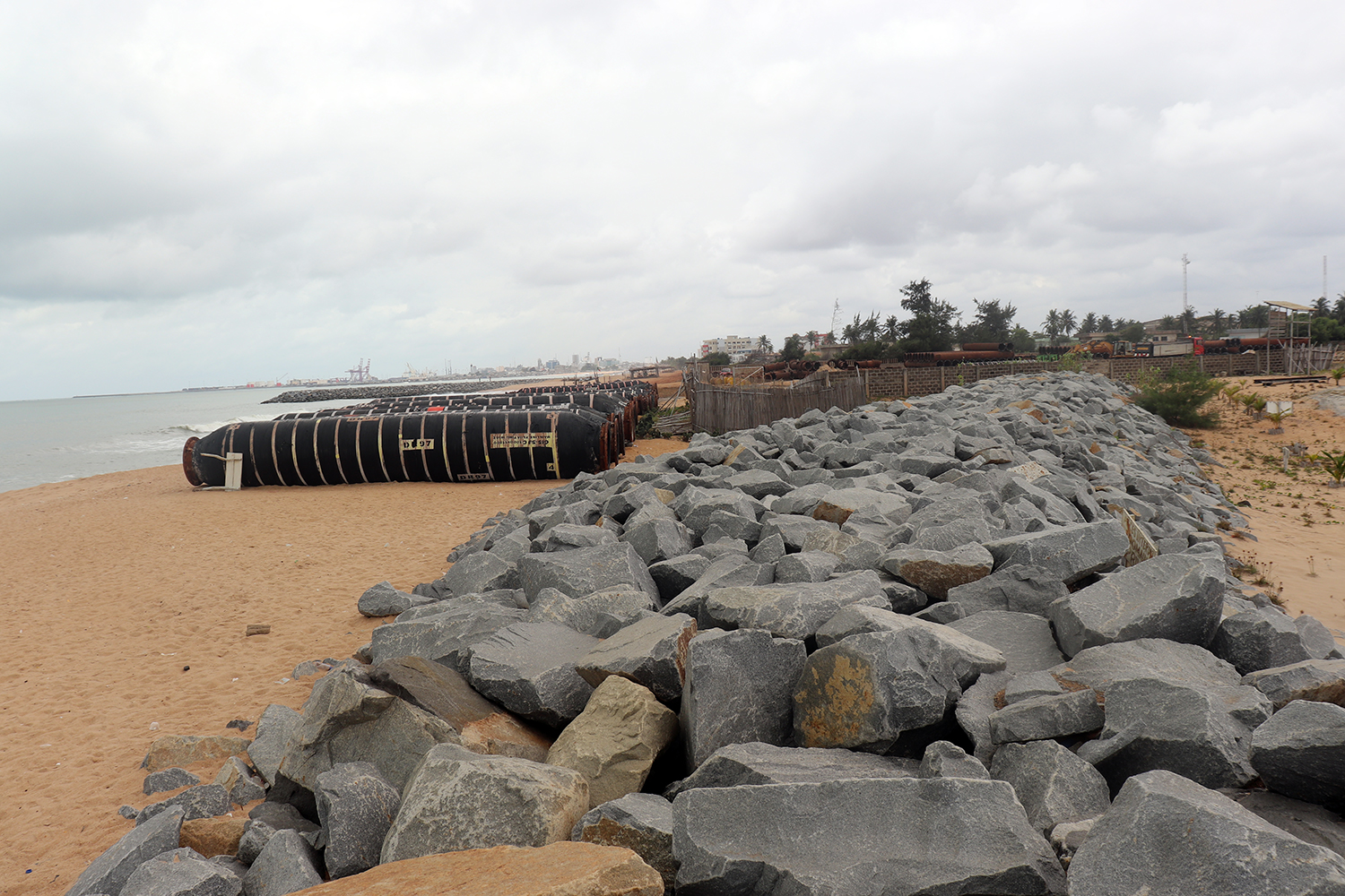 D’énormes tuyaux sont empilés sur la plage pour construire des canalisations qui freiner la violence de la mer.  