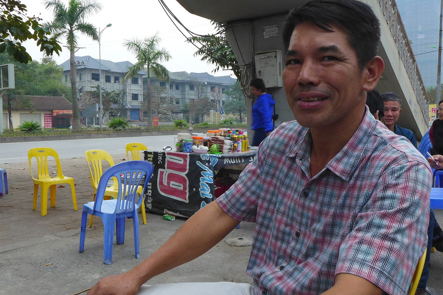 Hong Kha Truong, moniteur d’auto-école, fait une pause dans un café, assis sur un petit tabouret typique du Vietnam.