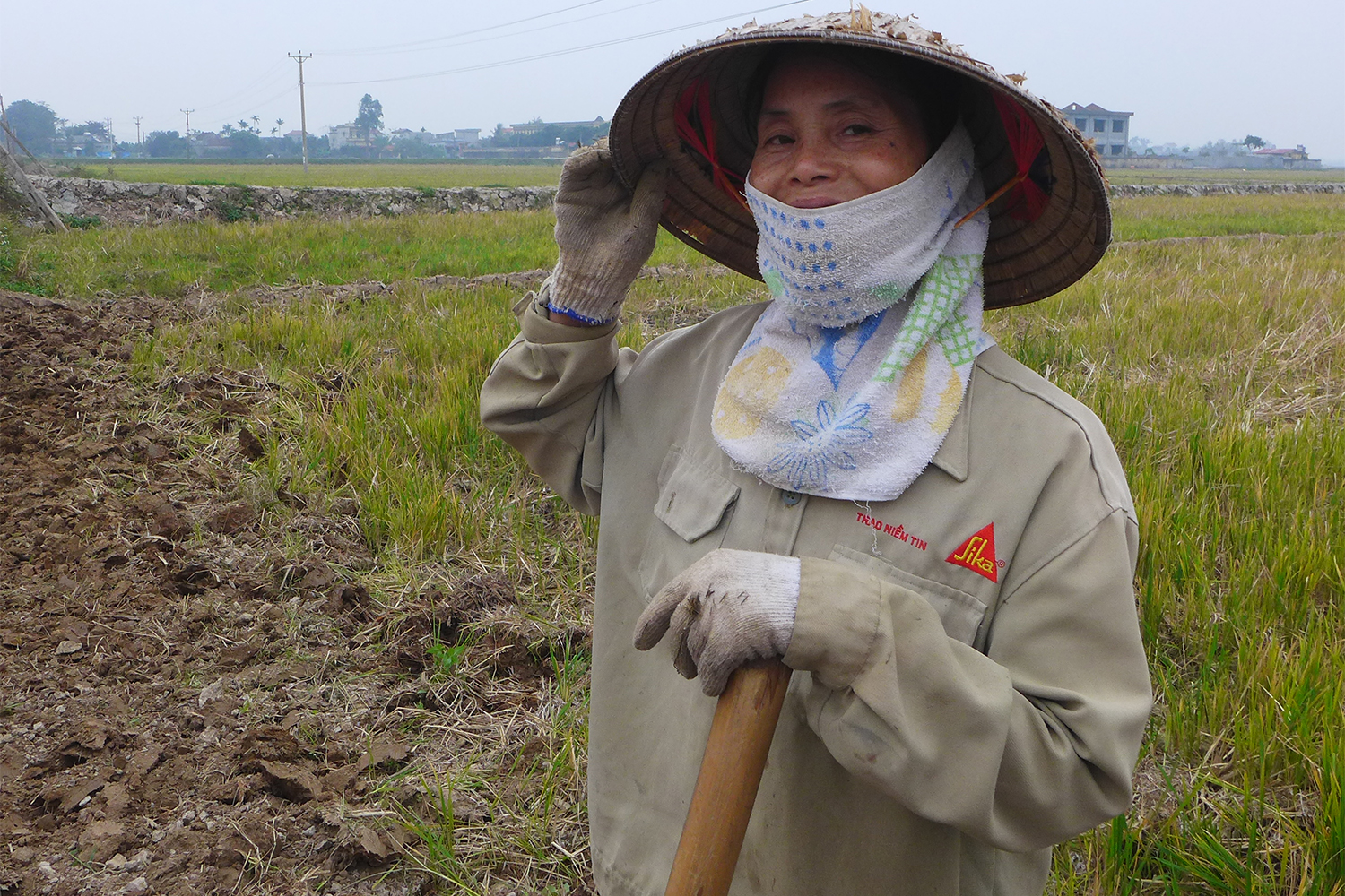 Mai porte un grand chapeau conique, typique du Vietnam. Cela lui permet de se protéger du soleil et de la pluie.