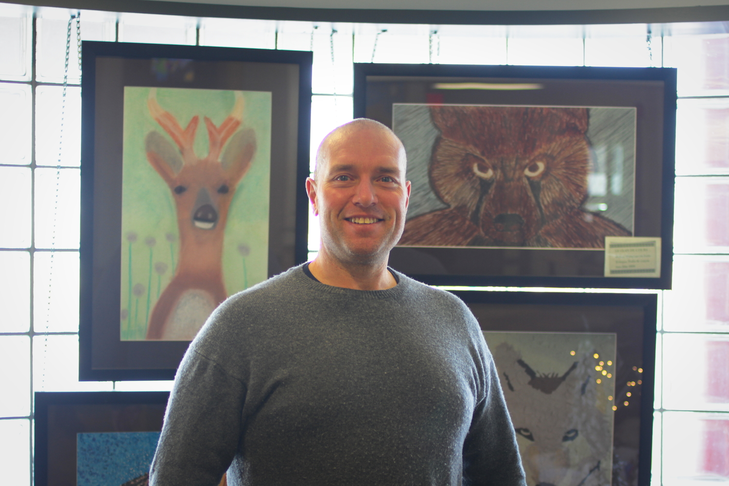 Le chef de famille Rémy VINCENT. Il est devant quatre peintures qui représentent les animaux des 4 clans wendats : le chevreuil, le loup, l’ours et la tortue.