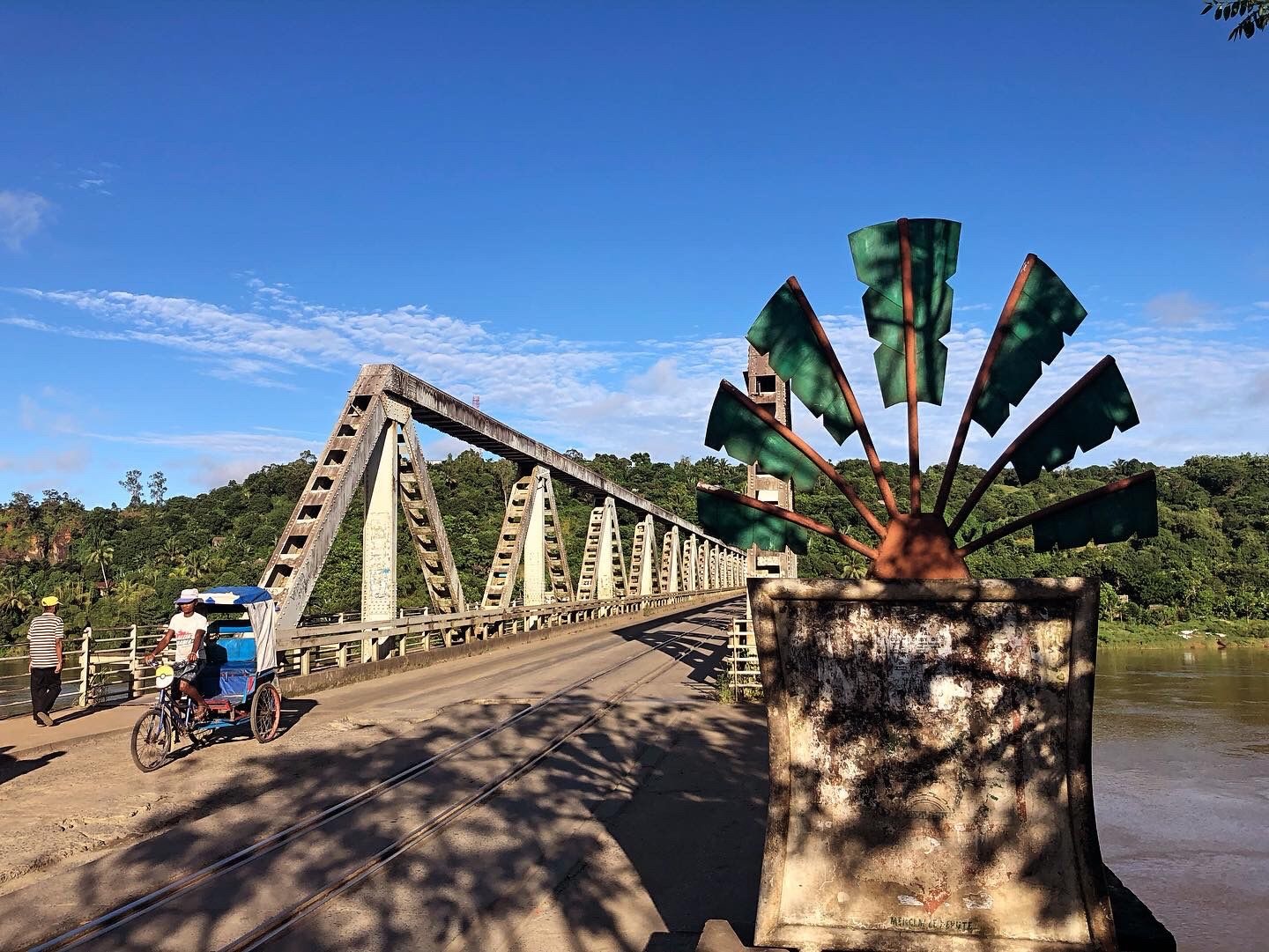 Pont sur la rivière Rianila à Brickaville et sculpture d’un des symboles du pays, le ravinala, un palmier en forme d’éventail qu’on utilise pour construire les maisons © Globe Reporters