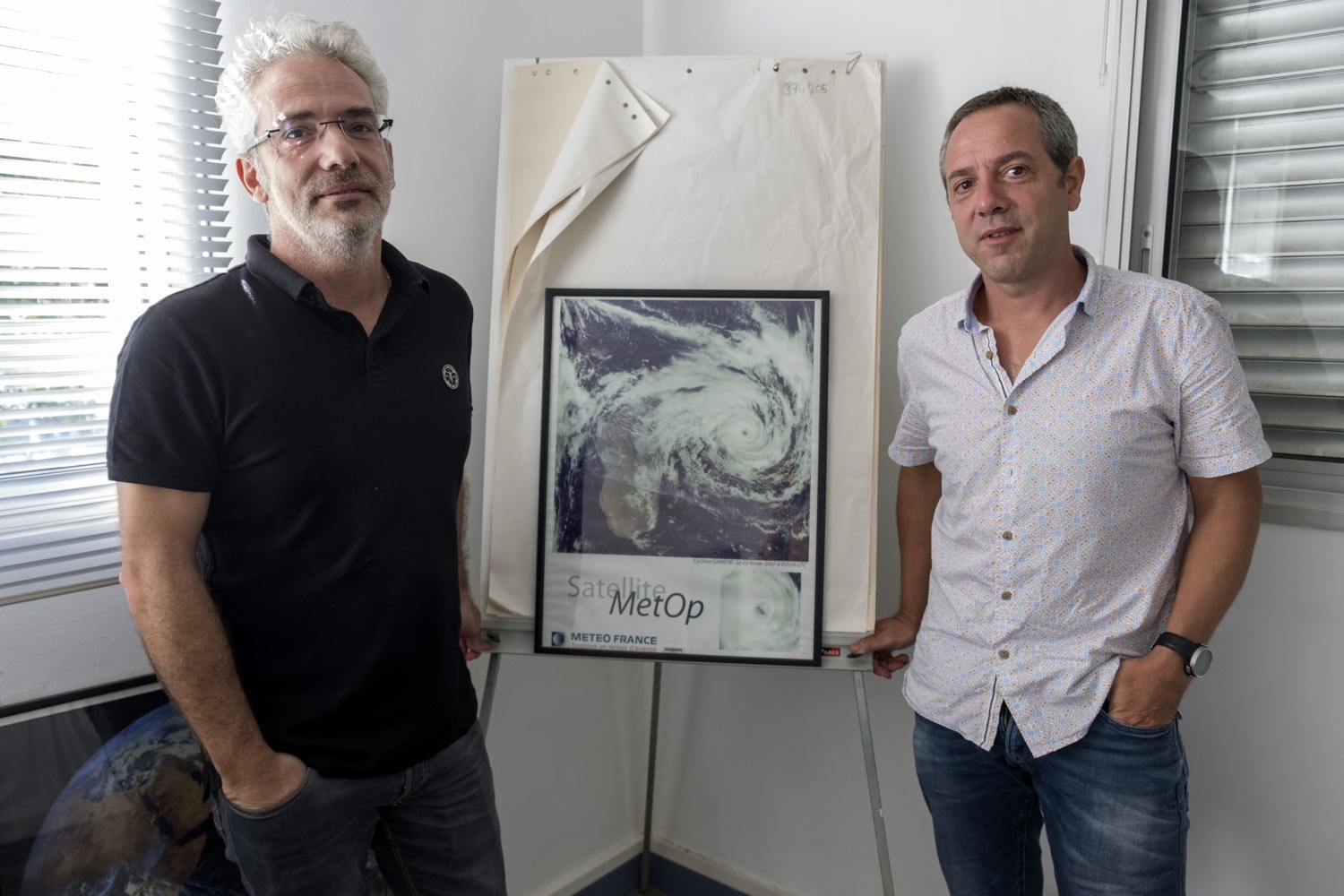 Olivier BOUSQUET et François BONNARDOT posent à côté d’une photo satellite du cyclone Gamète de 2007. 
