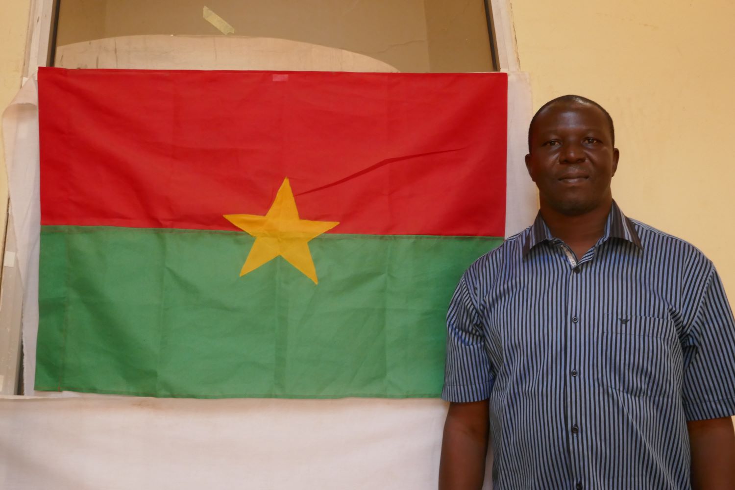 Sinaly DJIBO devant le drapeau de Burkina Faso © Globe Reporters