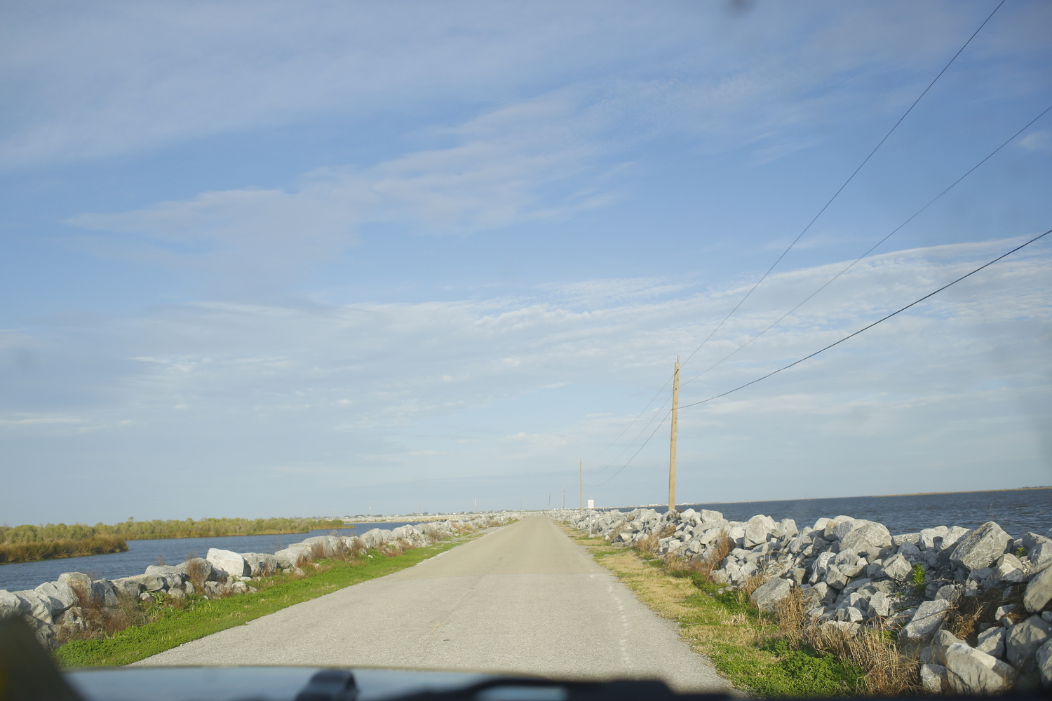 La route vers l’Isle de Jean Charles, désormais entourée par l’eau. Des pierres ont été installées pour éviter les inondations sur la route © Globe Reporters