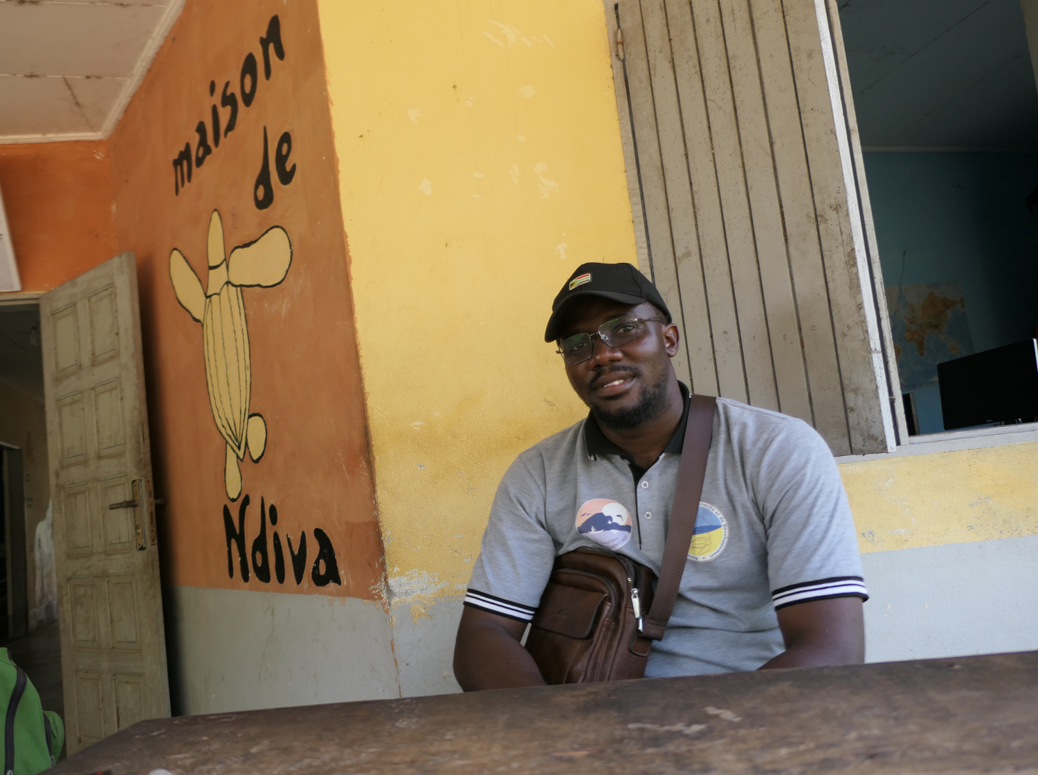 Xavier NDJAMO, coordinateur de l’association Tube Awu, devant la maison Ndiva qui accueille leurs locaux. Ndiva signifie “tortue luth” en langue Yassa