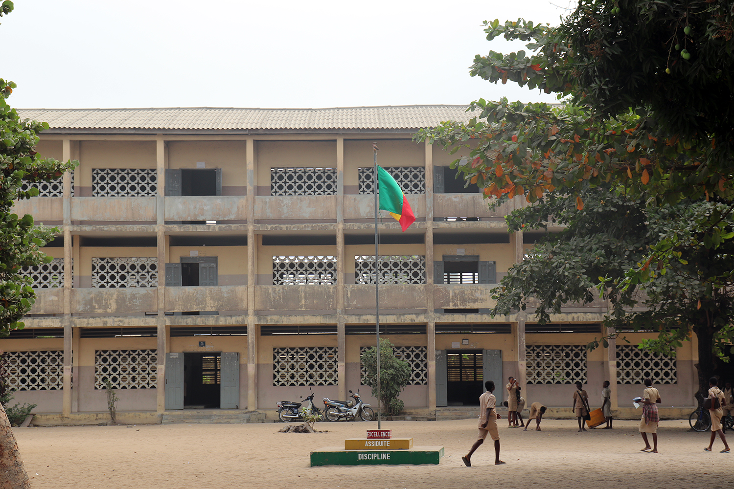 Bâtiment principal du collège avec le drapeau du Bénin au centre de la cour. 