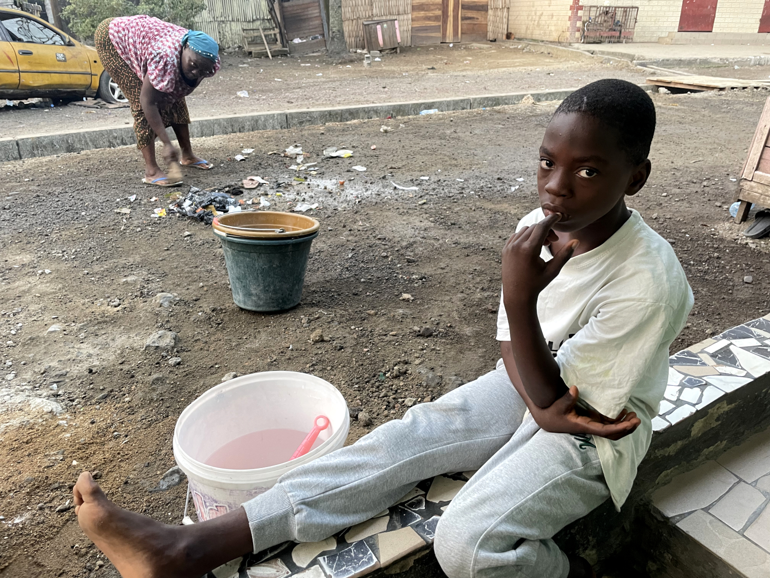 Lawani, son petit-fils, l’aide à préparer ses beignets avant d’aller à l’école © Globe Reporters