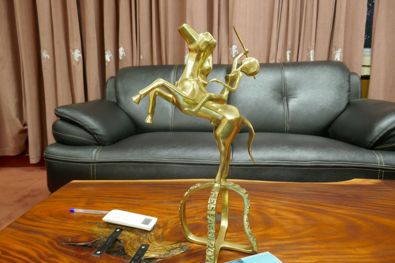 L’Étalon d’Or, statuette symbole du FESPACO que les lauréats et lauréates du Festival vont recevoir. Le trophée est posé sur la table devant l’envoyée spéciale, pendant qu’elle attend Alex Moussa SAWADOGO © Globe Reporters