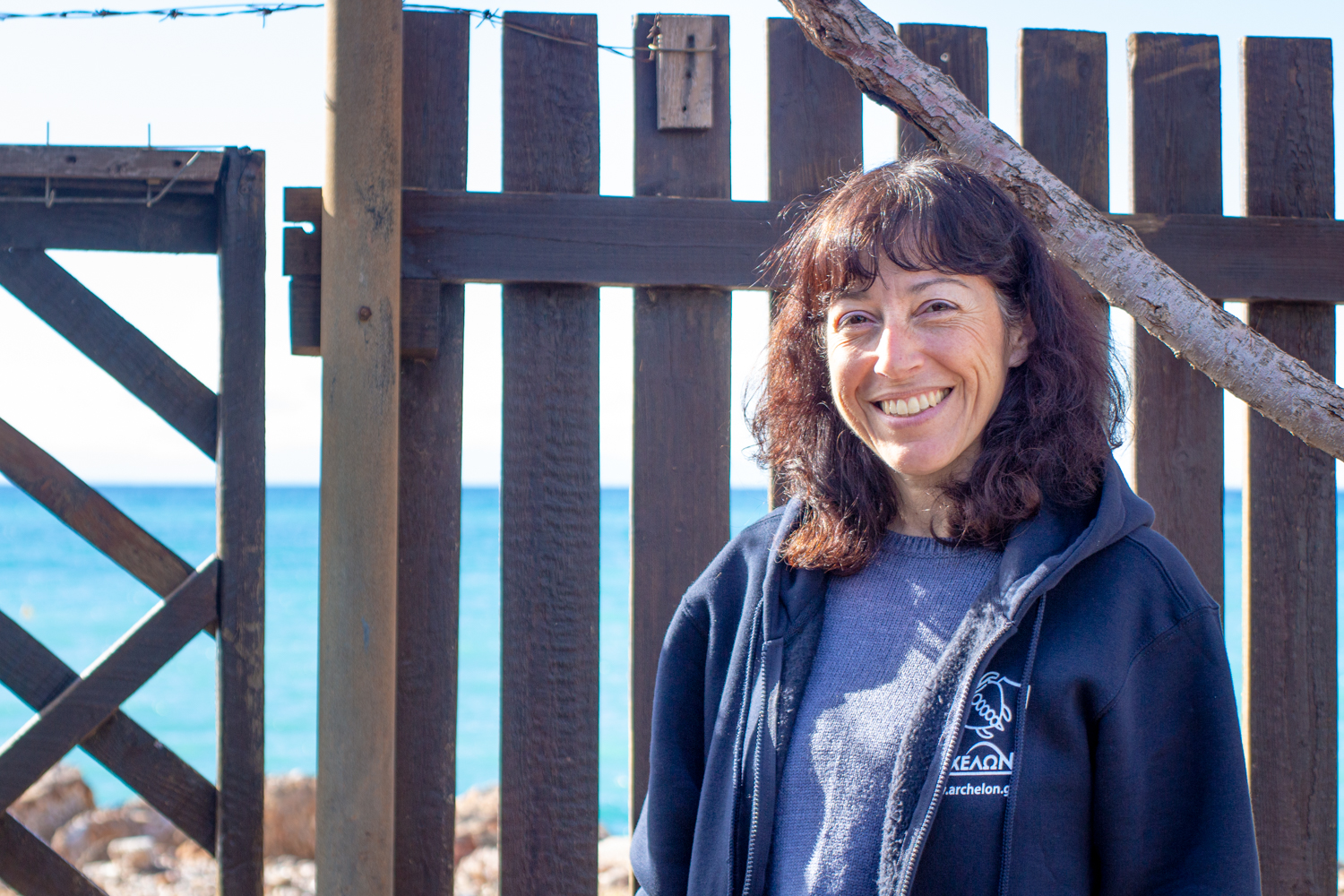 Anna KONDOLEON devant les palissades du centre de soins pour tortues de Glyfada, situé en bord de mer © Globe Reporters © Archelon