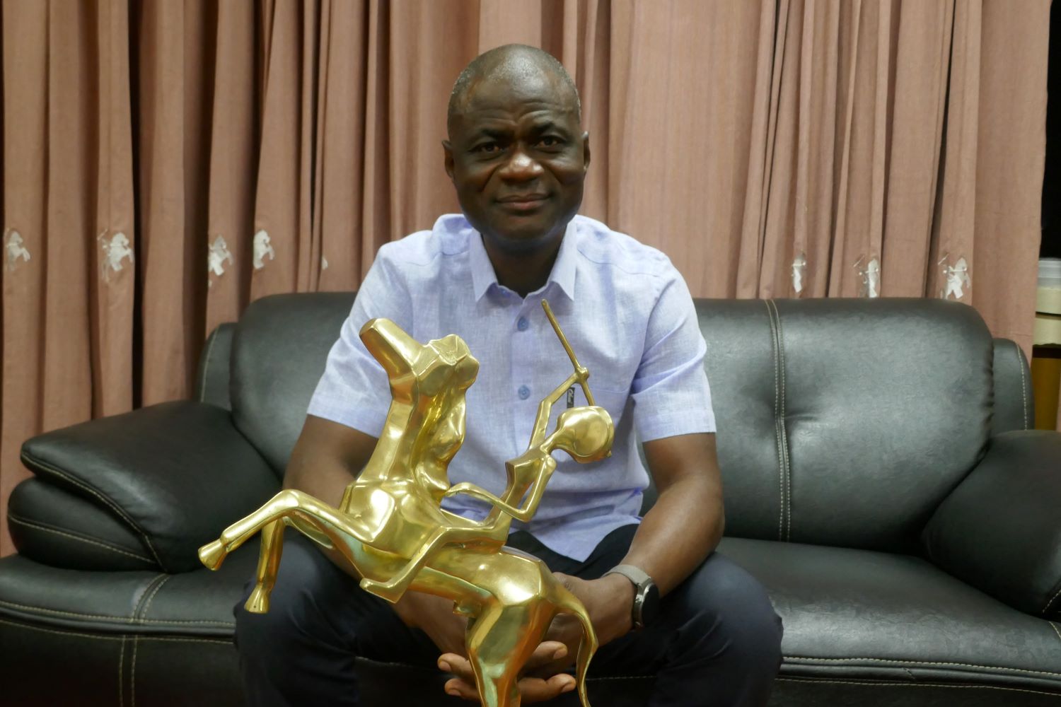 Portrait d’Alex Moussa SAWADOGO, directeur général du FESPACO, dans son bureau avec la statuette de l’Étalon d’Or © Globe Reporters