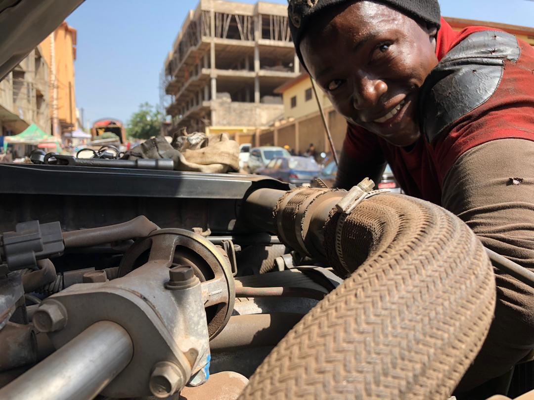 Première panne ; la climatisation. Le jeune Ibrahima SORY, qui affirme avoir 20 ans, tente une réparation de fortune dans la rue principale de Mamou. Sans succès. Notre envoyé spécial poursuit jusqu’à Faranah. 