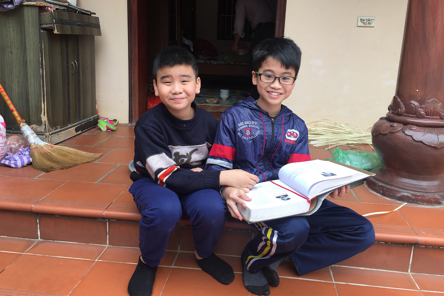 Dang (à droite) et son cousin Viet – surnommé Pamplemousse, le fils de Diep. Les enfants consultent un livre qui rassemble tous les noms des doctorants au Vietnam. Leur grand-oncle, qui a réalisé une thèse en doctorat en russe, y figure.