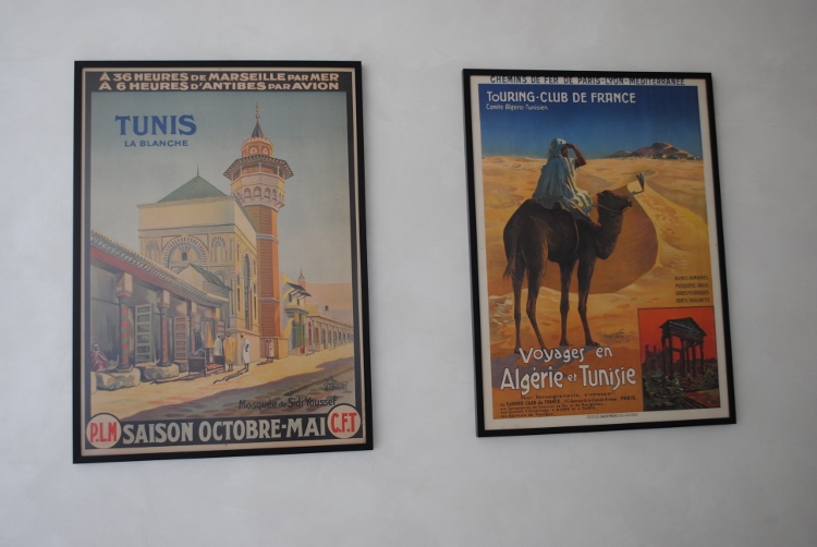 D’anciennes affiches publicitaires invitant au voyage en Tunisie sont accrochées sur un mur