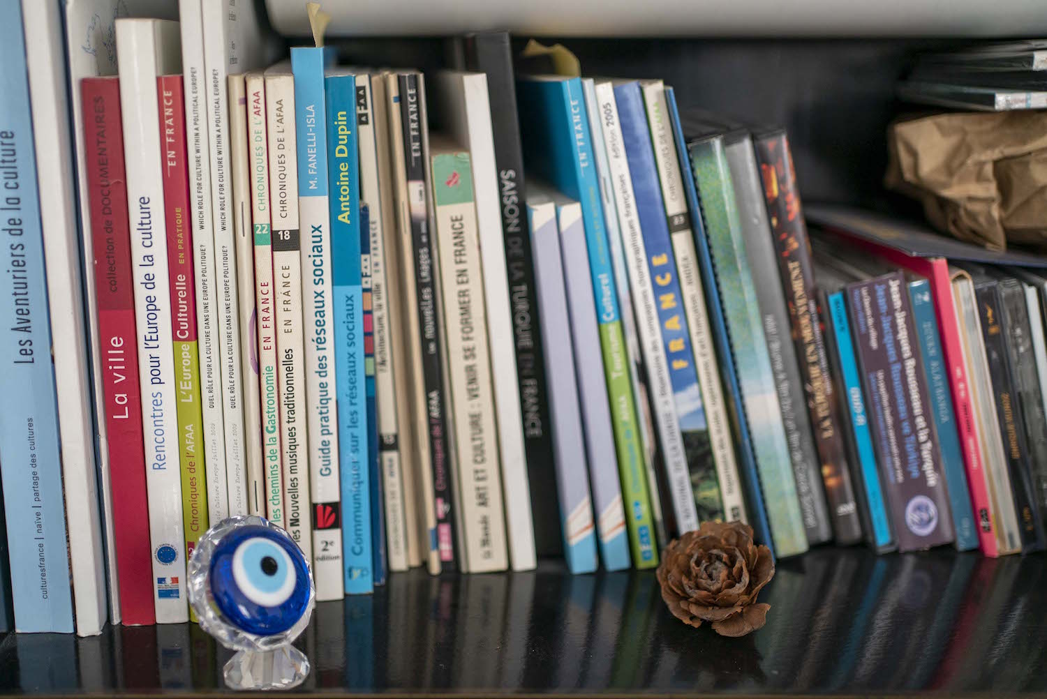 Sa bibliothèque est très fournie, mais il a pris soin d’y poser aussi un “nazar boncuk” (une amulette contre le mauvais œil) qui, en Turquie, est synonyme de chance. 