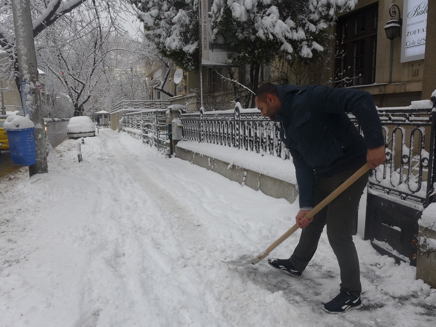 A l’aide d’une grosse pelle, chacun enlève  la neige du trottoir, devant chez lui.